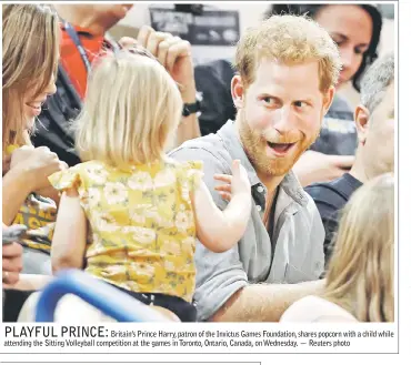  ??  ?? Britain’s Prince Harry, patron of the Invictus Games Foundation, shares popcorn with a child while attending the Sitting Volleyball competitio­n at the games in Toronto, Ontario, Canada, on Wednesday. — Reuters photo