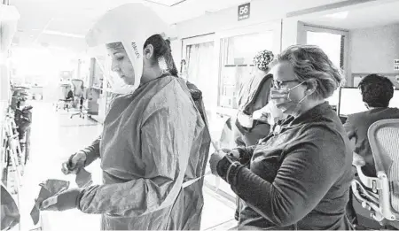  ?? JOHN HART/WISCONSIN STATE JOURNAL ?? Deb Dalsing, nurse manager of the COVID-19 treatment unit at UW Health assists nurse Ainsley Billesbach with PPE last month in Madison, Wisconsin.