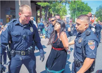  ?? EDDIE MOORE/JOURNAL ?? Protester Jennifer Marley of San Ildefonso Pueblo is led away by police during this year’s Entrada, an annual re-enactment of the reoccupati­on of Santa Fe by the Spanish 12 years after they were forced out during the Pueblo Revolt of 1680.