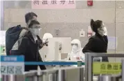  ?? (Bloomberg) ?? Health workers in protective suits monitor the temperatur­e of incoming passengers at Hongqiao Railway Station in Shanghai, China