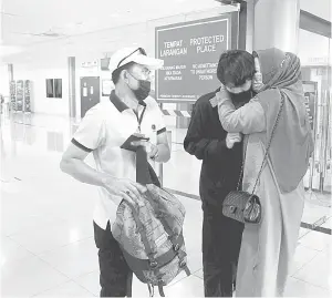  ?? — Gambar Bernama ?? SELAMAT TIBA: Mas Rika (kanan) ditemani suami Siyatno Harun, 52, (kiri) memeluk anak sulungnya Syafiq Aditya yang tiba di Kompleks Imigresen, Kastam, Kuarantin dan Keselamata­n (ICQS) Kota Laksamana di Melaka, kelmarin.