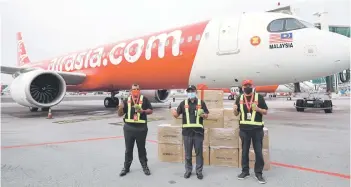  ??  ?? Ronald (middle) together with Fernandes (left) and Kamarudin are seen flagging off the first shipment of Harumanis mangoes to Sabah by airasia farm at klia2.