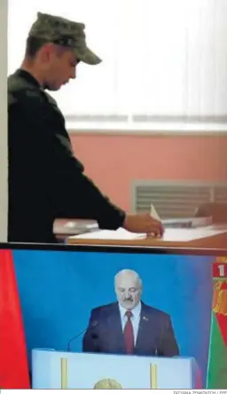  ?? TATYANA ZENKOVICH / EFE ?? Un soldado vota ayer en Minsk mientras comparece Lukashenko.