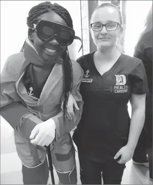  ??  ?? Above: Samantha Baako, left, and Claudia Tomcyzk are health careers students at Davies Tech. Baako is wearing an age-simulating suit at the state education showcase held at Davies on Tuesday.