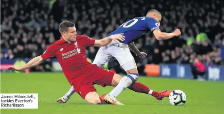  ??  ?? James Milner, left, tackles Everton’s Richarliss­on