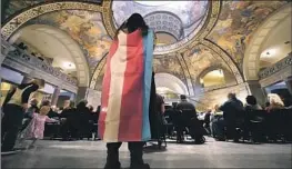  ?? Charlie Riedel Associated Press ?? OFFICIALS in Kansas City, Mo., are moving to declare it a sanctuary for genderaffi­rming care. Above, a protester wears a transgende­r flag at the Statehouse.