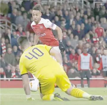  ?? — AFP photo ?? Arsenal’s Gabonese striker Pierre-Emerick Aubameyang scores the team’s third goal past Rennes’ Czech goalkeeper Tomas Koubek during the UEFA Europa League Round of 16 second leg football match between Arsenal and Rennes at the Emirates Stadium in London.