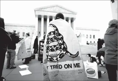  ?? LUKE SHARRETT / NEW YORK TIMES FILE (2012) ?? A tea party activist wrapped in a Gadsden flag stages a demonstrat­ion in 2012 outside the Supreme Court. The court will consider this week a case from Minnesota in which a man was temporaril­y delayed from voting because he wore a shirt displaying the...