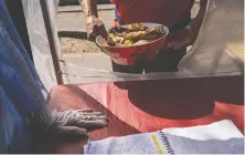  ?? TAMARA MERINO/ BLOOMBERG ?? A resident receives a meal in Santiago, Chile. The meals are funded with donations that are starting to stretch thin.