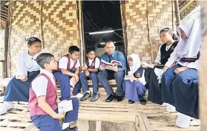  ?? — Gambar Bernama ?? UNTUK MASA DEPAN MEREKA: Guru Bahasa Melayu Mohd Asmadi Zainal Abidin bersama tujuh murid SK Pos Musoh LZ mengulangk­aji pelajaran pada waktu rehat sebelum menduduki mata pelajaran Bahasa Melayu (Penulisan) pada UPSR di Tapah, semalam.