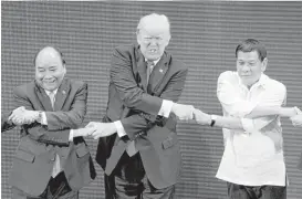  ?? Andrew Harnik / Associated Press ?? President Donald Trump does the “ASEAN-way handshake” on Monday with Vietnamese President Tran Dai Quang, left, and Philippine President Rodrigo Duterte on stage during the opening ceremony at the ASEAN Summit.