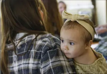  ?? Nate Billings/Associated Press ?? One-year-old Cora Dibert is held by her mother, Morgan Shurtleff, at The Bridge Church earlier this month in Mustang, Okla. The child has been diagnosed as having lead poisoning.