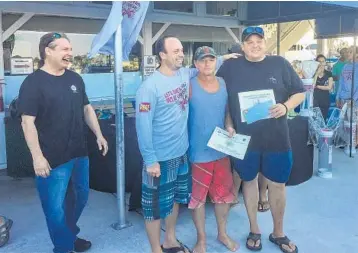  ?? GABBY MAGALSKI/COURTESY ?? David Ventura, seafood coordinato­r for Whole Foods Market, far left, and team Pain Killer accept their first-place award for catching the most lionfish: 206. They also took home the prize for largest lionfish, at more than 16 inches.