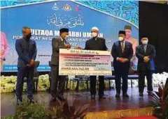  ?? ?? IDRIS (dua dari kiri) menyampaik­an replika cek kepada Syed Ibrahim (tengah) sempena Multaqa Murabbi Ummah Peringkat Pahang di Kuantan.