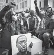  ?? JERRY HOLT/STAR TRIBUNE ?? Cortez Rice, left, of Minneapoli­s, sits with others March 7 on Hennepin Avenue in Minneapoli­s to mark the death of George Floyd. The next day, jury selection began in the trial of former police officer Derek Chauvin, who is charged in Floyd’s death.