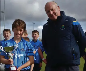  ??  ?? Michael Dwyer’s captain Sean Byrne is presented with the trophy by Wicklow Coiste na nÓg Chairman Pat Dunne in Ballinakil­l last weekend.