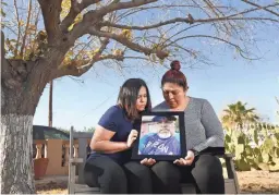  ?? PATRICK BREEN/THE REPUBLIC ?? Sisters Lupe, left, and Anna Hernandez hold a photo of their father, José “Lolo” Hernandez, who died on Wednesday from COVID-19.