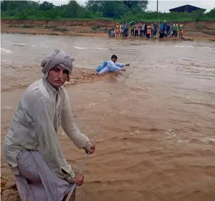  ?? AFP ?? Men trying to cross flood waters in Deesa municipali­ty, which has been hit by severe flooding along the Banas River, in northern Gujarat. —