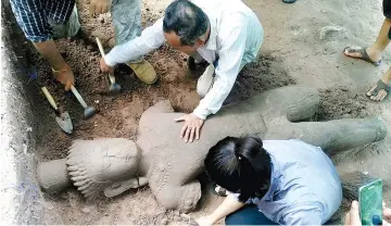  ??  ?? This handout photo taken on July 30 and released on Aug 1 by the Apsara Authority – the state agency charged with managing the Angkor temple complex, shows archaeolog­ists excavating a statue from the ground at the complex in Siem Reap province. — AFP...