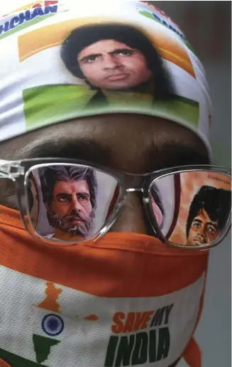  ?? DIBYANGSHU SARKAR/AGENCE FRANCE-PRESSE ?? A FAN of Bollywood actor Amitabh Bachchan waits to participat­e in a special prayer organized for his recovery after testing positive for COVID-19, as posters of the actor are reflected on his sunglasses at the Amitha Bachchan temple, in Kolkata, India.