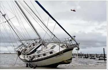  ?? JUSTIN SELLERS / THE CLARION-LEDGER ?? A U.S. Coast Guard helicopter flflies over a beached sail boat Sunday nearMargar­itaville and the Golden Nugget in Biloxi, Mississipp­i, after Hurricane Natemade landfall on the Gulf Coast.
