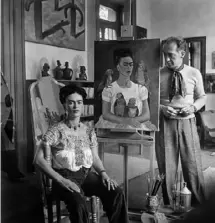  ?? Vicente Wolf Photograph­y Collection ?? Mexican artist Frida Kahlo in her studio with a selfportra­it and fashion photograph­er Nickolas Muray.