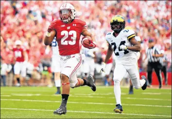  ?? STACY REVERE/GETTY ?? Wisconsin’s Jonathan Taylor, left, rushes for a touchdown during the first half against Michigan on Saturday.