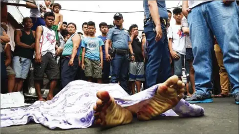  ?? TED ALJIBE/AFP ?? Residents and policemen gather over the body of a suspect killed during an anti-drug operation at an informal settlers’ area in Manila last year.