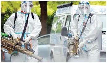  ?? ?? Dragged away: Authoritie­s in hazmat suits manhandle a resident in Shanghai and (top) use gun-like devices to disinfect a community