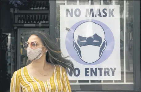  ?? JAE C. HONG — THE ASSOCIATED PRESS FILE ?? A woman walks out of a liquor store past a sign requesting its customers to wear a mask Tuesday, in Santa Monica According to a new poll, Americans overwhelmi­ngly are in favor of requiring people to wear masks around other people outside their homes, reflecting fresh alarm over spiking infection rates. The poll also shows increasing disapprova­l of the federal government’s response to the pandemic. California is among the states seeing the greatest surge in cases now.