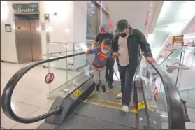  ??  ?? Yancarlos Amaya leaps off an escalator while holding the hand of family friend Dimas Barahona at the airport.