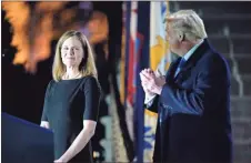  ?? AP-Patrick Semansky ?? President Donald Trump looks toward Amy Coney Barrett, before Supreme Court Justice Clarence Thomas administer­s the Constituti­onal Oath to her on the South Lawn of the White House Monday after Barrett was confirmed by the Senate earlier in the evening.