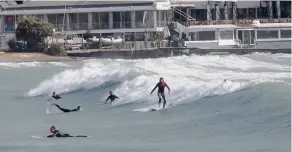  ??  ?? Surfers brave the chilly weather to take advantage of unusually big waves in Vouliagmen­i, south of Athens, yesterday. While winds reached gale-force in parts, they were southerly and pushed up temperatur­es.