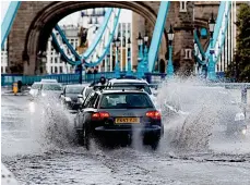  ??  ?? Making waves... traffic by a flooded Tower Bridge, London