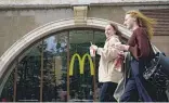  ?? NATALIA KOLESNIKOV­A/AFP VIA GETTY IMAGES ?? Women walk past a closed McDonald’s in Moscow on Monday.