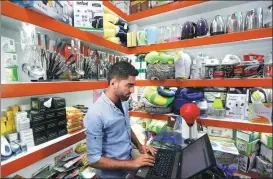  ?? OMAR SOBHANI / REUTERS ?? An Afghan shopkeeper works on his laptop at his online store in Kabul, Afghanista­n on June 4.