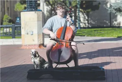  ?? Kathryn Scott, The Denver Post ?? Michael Casey, accompanie­d by his dog, Symon, plays the cello on the Pearl Street Mall in Boulder this month. The music rises above the constant noise of footsteps and the shouts from a nearby street performer.