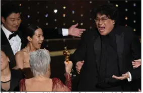  ?? (AP/Chris Pizzello) ?? Parasite director Bong Joon Ho (right) reacts as Jane Fonda presents him with the Oscar for best picture during Sunday night’s ceremony at the Dolby Theatre in Los Angeles. Bong, who earlier won the award for best director, was joined onstage by Parasite cast members including Kang-Ho Song (left) and Kwak Sin Ae.