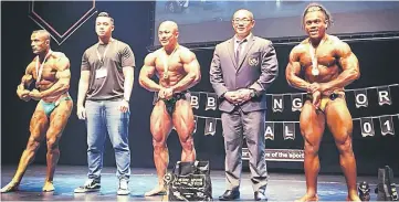  ??  ?? Jeremiah (centre) joins runners-up Ehab (left) and Mohamad (right) in a victory pose after the prize presentati­on. Also seen is IFBB Malaysia president Edmund Chong (second right).