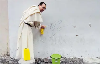  ?? GONZALO MARTÍNEZ ?? 1 1. Un sacerdote domínico en el Pasaje 5 de Julio, en San Telmo, borra un graffiti pro aborto.