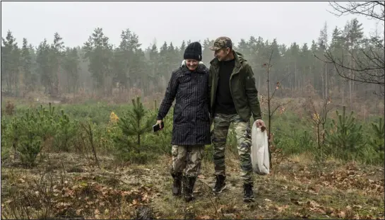  ?? PHOTOS BY BRENDAN HOFFMAN — THE NEW YORK TIMES ?? Dmytro and Yana Poyedynok search for mushrooms in the Bucha area of Ukraine on Nov. 3. Officials say there have been reports of mushroom hunters in multiple regions stepping on mines.