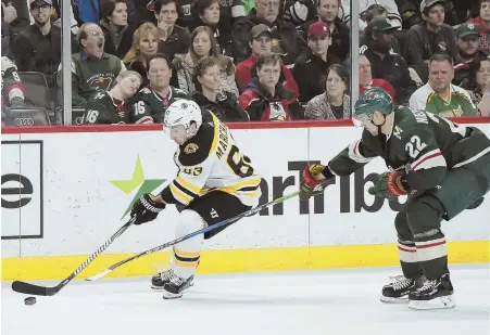  ?? AP PHOTO ?? CAN'T SLOW HIM DOWN: Brad Marchand controls the puck while being checked by the Wild's Nino Niederreit­er during the Bruins' 2-1 overtime victory Sunday night in St. Paul, Minn.