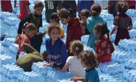  ?? Photograph: Mohamed Njm/Medialys/Rex ?? Displaced Syrian children with water delivered to a camp near Kafr Uruq, Idlib, in August. The UN must buy goods in Syria with currency exchanged through the central bank.