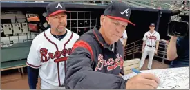  ?? / ap ?? Atlanta Braves manager Brian Snitker, right, signs a get well card for former Braves manager Bobby Cox who reportedly is being hospitaliz­ed after suffering a stroke on Thursday in Atlanta. Bench coach and former Braves infielder Walt Weiss looks on.