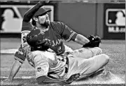  ?? NATHAN DENETTE/AP ?? Lorenzo Cain slides under the tag of Blue Jays pitcher R.A. Dickey to score on a first-inning passed ball Tuesday.