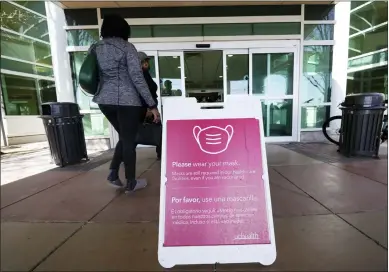  ?? DAVID ZALUBOWSKI/ASSOCIATED PRESS ?? A sign advising visitors to don face coverings stands outside the main entrance to Uchealth University of Colorado hospital Friday, April 1, 2022, in Aurora, Colo. COVID cases are starting to rise again in the United States, with numbers up in most states and up steeply in several. One expert says he expects more of a “bump” than the monstrous surge of the first omicron wave, but another says it’s unclear how high the curve will rise and it may be more like a hill.