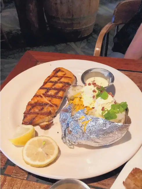  ?? JASON K. WATKINS/FOR THE JOURNAL ?? The grilled salmon is served with a loaded baked potato at Pelican’s Steak &amp; Seafood.