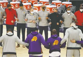  ?? CHRISTIAN PETERSEN/ GETTY IMAGES ?? Members of the Suns and Raptors stand arm-in-arm during the U.S. national anthem in a show of solidarity before Wednesday night's game in Phoenix, Ariz.