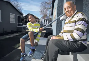  ?? Liz Hafalia / The Chronicle ?? Ronald Calbert sits on the steps of his West Oakland home with his godson, Marvell Marshall, 8.