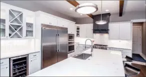  ??  ?? Radiant white quartz countertop­s and an island with a breakfast bar accentuate the kitchen.